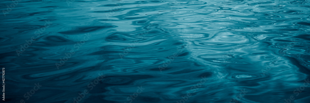 Abstract blue green background. Reflection of sunlight on a wavy water surface. Ripples. Beautiful teal background with copy space for design. Web banner. Abstract blue green background. Reflection of sunlight on a wavy water surface. Ripples. Beautiful teal background with copy space for design. Web banner.