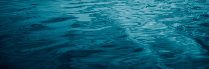 Abstract blue green background. Reflection of sunlight on a wavy water surface. Ripples. Beautiful teal background with copy space for design. Web banner.