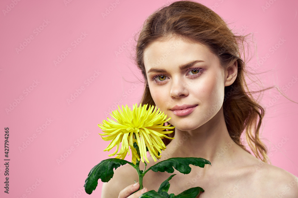 Portrait of a woman with yellow flowers on a pink background Makeup on the face Portrait of a woman with yellow flowers on a pink background Makeup on the face