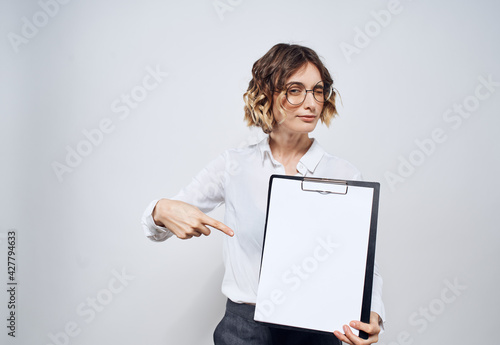 Business woman holds in her hands a folder with a white sheet on a light background