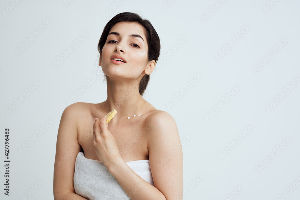 Beautiful brunette with a sponge in her hands white towels clean skin care Beautiful brunette with a sponge in her hands white towels clean skin care