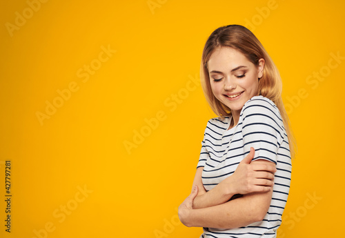 Happy blond woman with closed eyes on a yellow background
