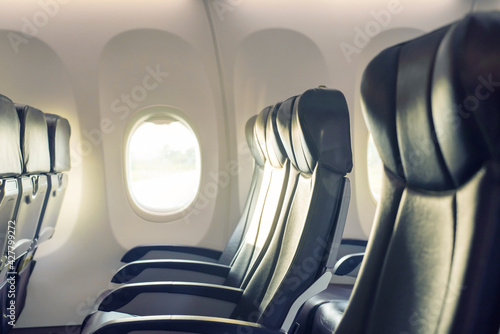 Empty seats in the airplane cabin and a window with blue sky view