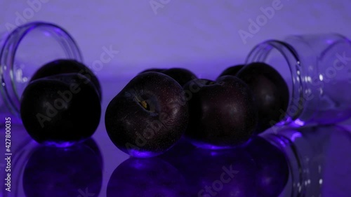 Plum joins a Group of Plums on a Glass Table with Purple Light - SlowMotion photo