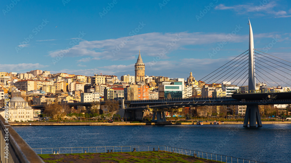 Fototapeta premium Scenic view of modern cityscape of Beyoglu district in Istanbul across Bosphorus and Golden Horn bay with views of cable-stayed metro bridge on sunny winter day, Turkey