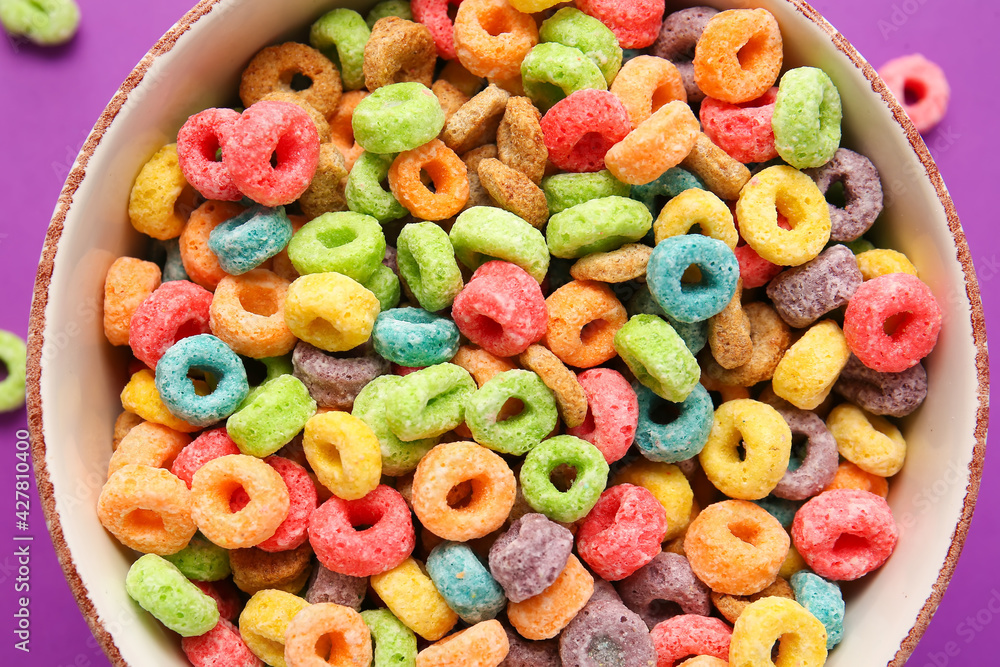 Bowl with tasty cereal rings on color background, closeup