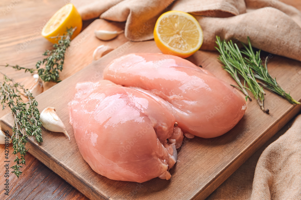Board with raw chicken fillet on wooden background, closeup Board with raw chicken fillet on wooden background, closeup