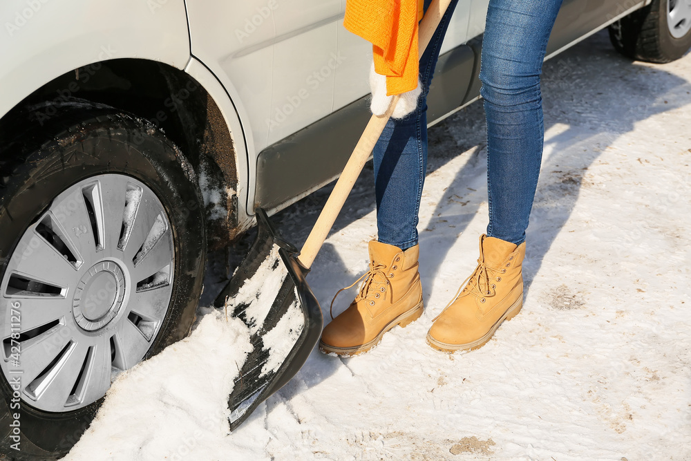 Woman removing snow near her car on winter day Woman removing snow near her car on winter day