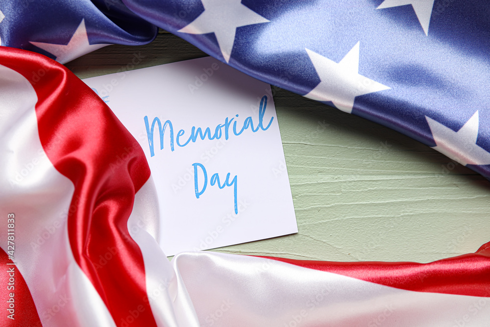 Paper sheet with text MEMORIAL DAY and USA flag on color wooden background Paper sheet with text MEMORIAL DAY and USA flag on color wooden background