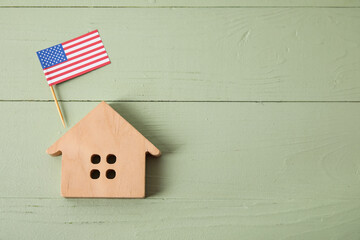 Figure of house and USA flag on color wooden background