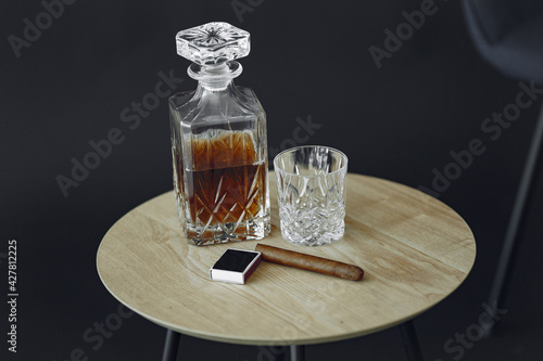 Bottle and glass of brandy and cigar on wooden table
