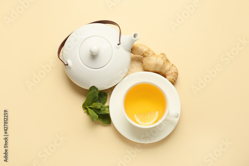 Teapot and cup of tea with ginger on color background