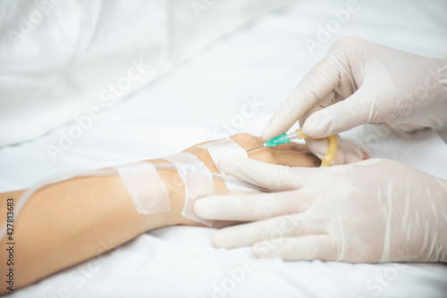 A nurse gentle injection with the medical into patient’s hand, The Dr. giving an vaccine to patient while lying in Hotpital bed. soft focus.