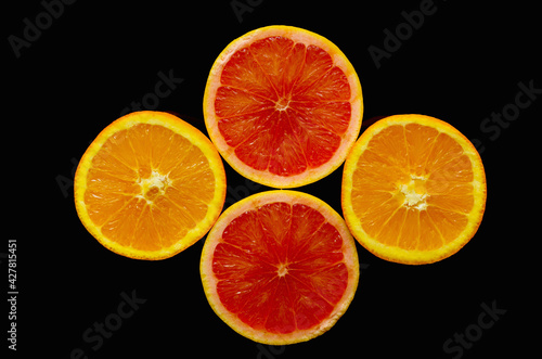 Composition with orange and grapefruit slices on a black background.