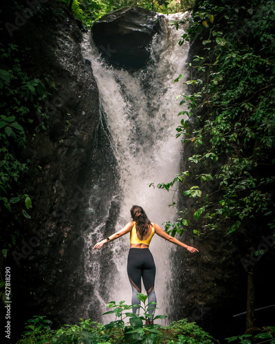 Happy woman enjoying beautiful waterfall in the mountain