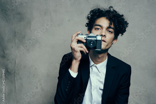photographer with camera indoors on gray background and jacket curls shirt model