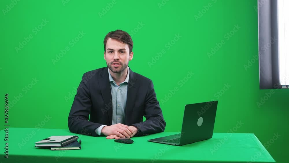 Man reporter sits in the studio and looks into the camera, speaks and hosts a news programon a green background, a template for TV news agencies, journalist at work, chromakey. Man reporter sits in the studio and looks into the camera, speaks and hosts a news programon a green background, a template for TV news agencies, journalist at work, chromakey.