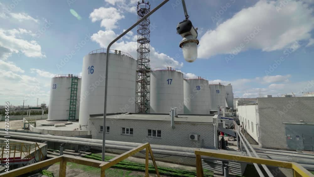 White storage tanks for liquids in a modern factory. Large storage tanks in the factory. Storage tanks of an oil refinery. White storage tanks for liquids in a modern factory. Large storage tanks in the factory. Storage tanks of an oil refinery.