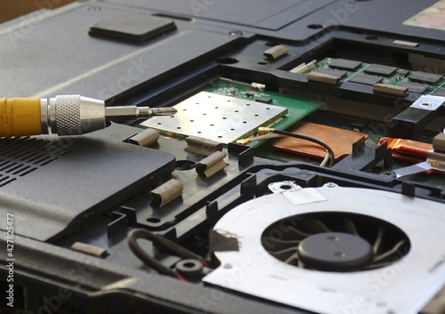 Disassembled the laptop for repair, screwdriver close-up