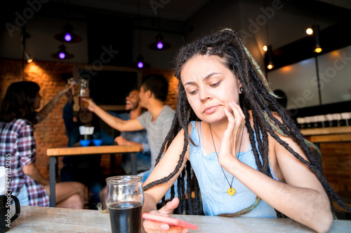 A girl alone with her phone in a bar
