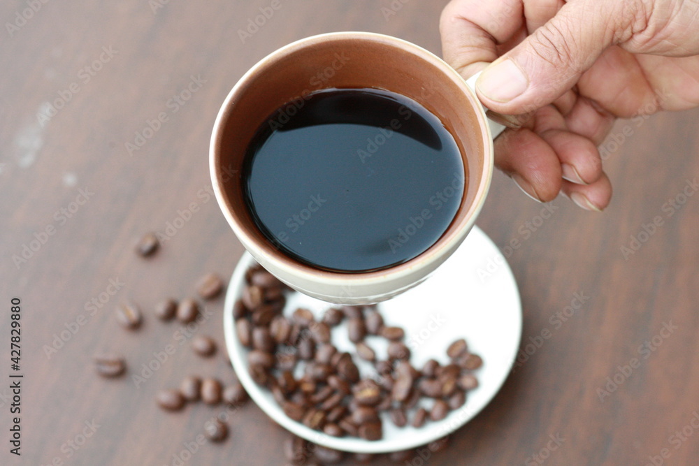 Fototapeta premium Close up at Old man hand pick up a cup of coffee for drinking in the morning.Elderly lifestyle.People famous take black coffee for freshness.Top view.