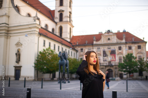 Stylish young girl in a black dress on the street of the city of BRNO in the morning.Czech