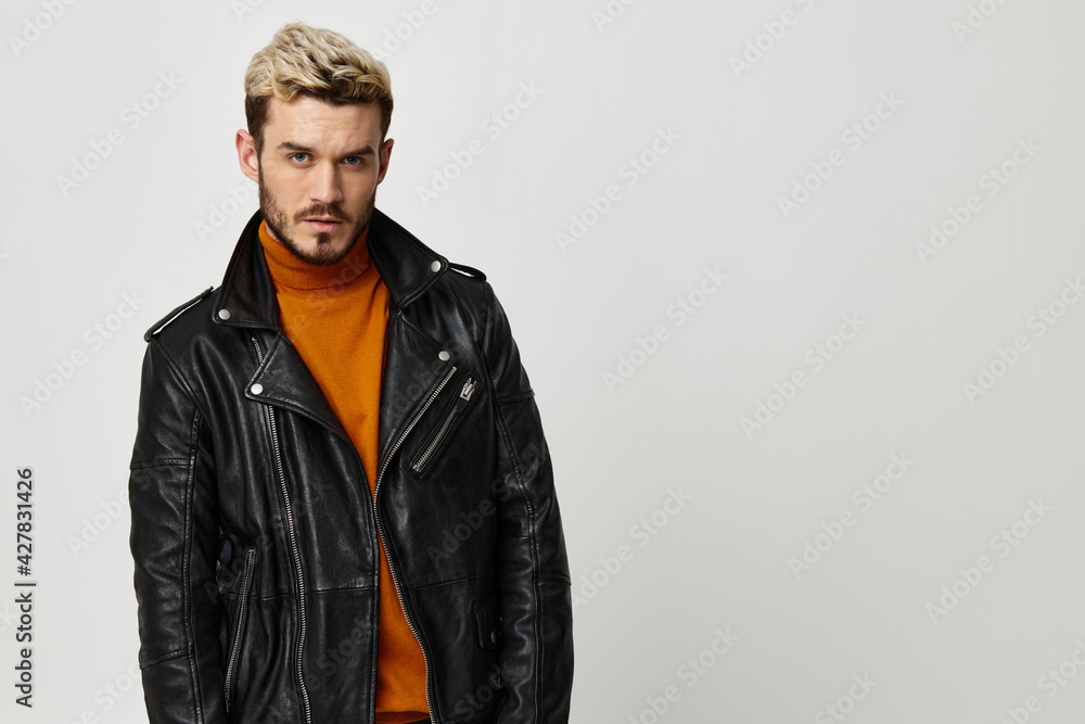 young man in leather jacket blond orange sweater light background young man in leather jacket blond orange sweater light background