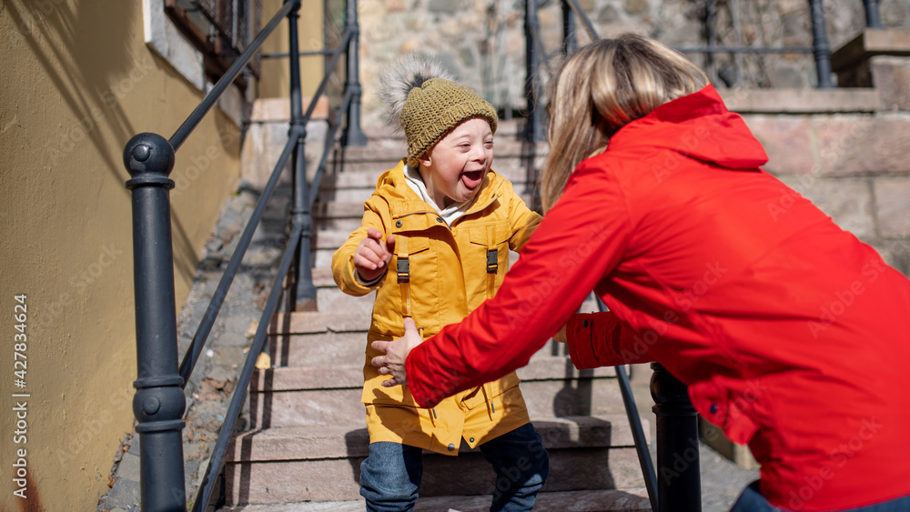 Single mother with down syndrome child outdoors in town, having fun. Single mother with down syndrome child outdoors in town, having fun.