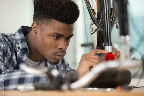 black mechanic removing bicycle rear cassette in a workshop