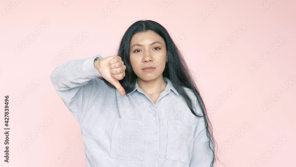 I dont like this. Dissatisfied unhappy serious hispanic pretty woman showing thumbs down dislike gesture, critiquing bad service. Indoor studio shot isolated on pink background I dont like this. Dissatisfied unhappy serious hispanic pretty woman showing thumbs down dislike gesture, critiquing bad service. Indoor studio shot isolated on pink background