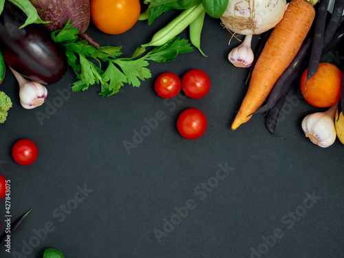 Frame of various vegetables on dark background, top view.