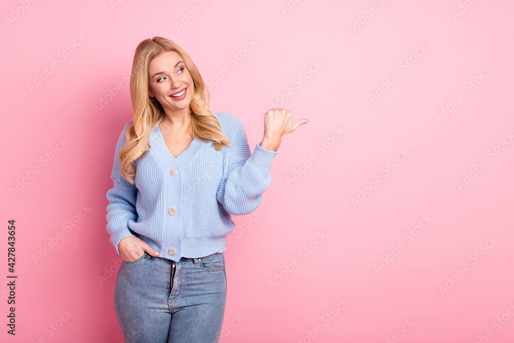 Photo portrait of woman curious looking pointing thumb blank space promoting isolated on pastel pink color background Photo portrait of woman curious looking pointing thumb blank space promoting isolated on pastel pink color background