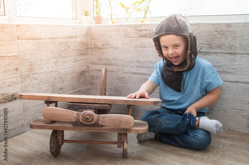 Boy with Down syndrome in a pilot's helmet next to the plane.
 photo