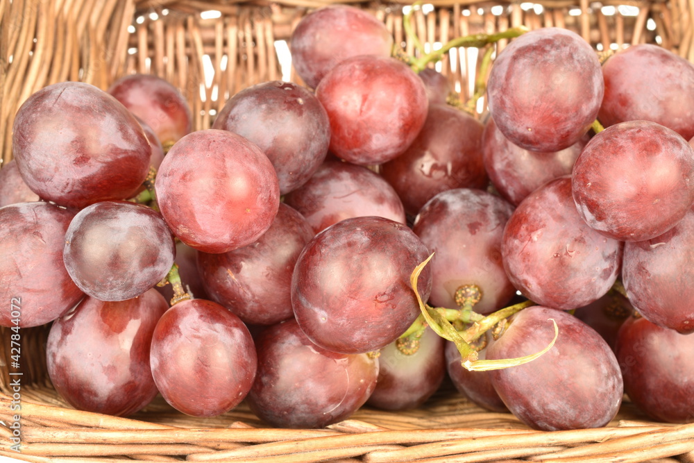 A bunch of fresh organic, juicy, ripe, sweet grapes with a wicker basket of vines, close-up. A bunch of fresh organic, juicy, ripe, sweet grapes with a wicker basket of vines, close-up.