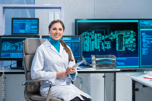 Female microelectronics engineer works in a scientific laboratory on computing systems and microprocessors. Professional electronic factory worker is testing the motherboard and coding the firmware. photo