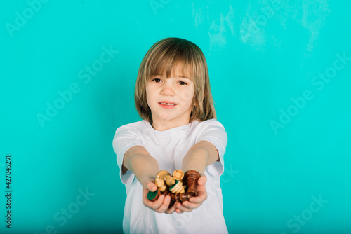 Cute kid holding a game of chess in his arms, studio shooting