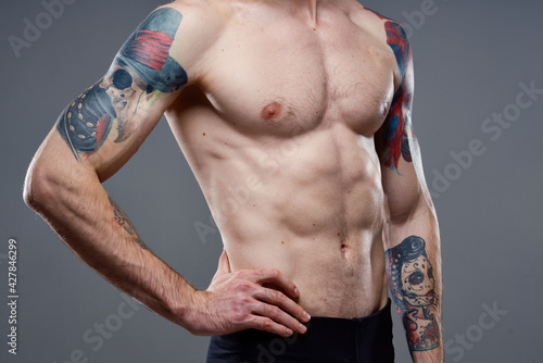 sporty man with a pumped-up torso tattoo on his arms cropped view model