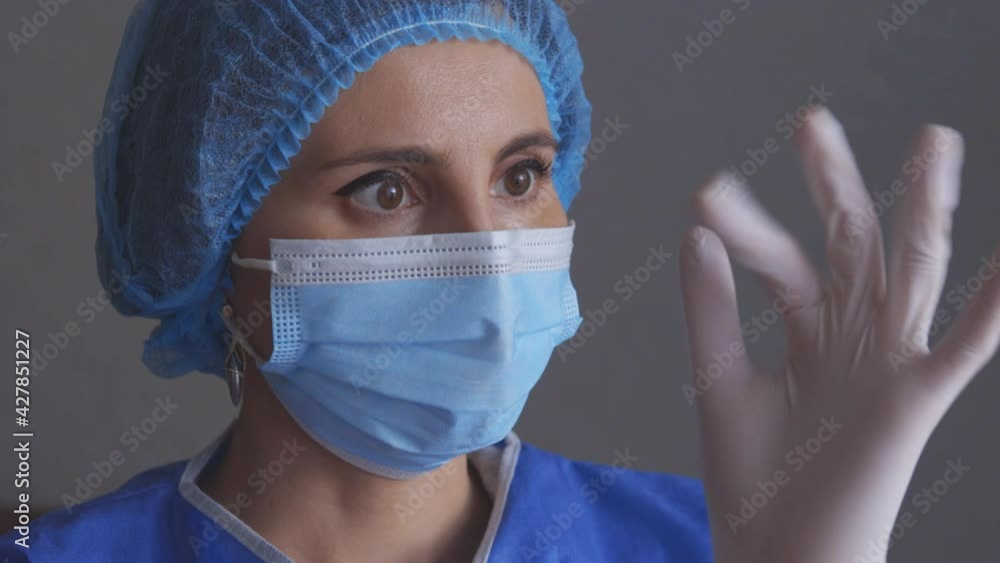 A close up shot of a female doctor or health care worker in personal protective kit preparing and wearing hand gloves in the interior hospital A close up shot of a female doctor or health care worker in personal protective kit preparing and wearing hand gloves in the interior hospital