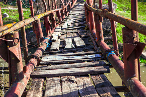 Old footbridge with balustrade and broken wooden planks 