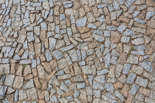 Standard view of granite sidewalk with irregular pairing, characteristic texture with moss in the joints