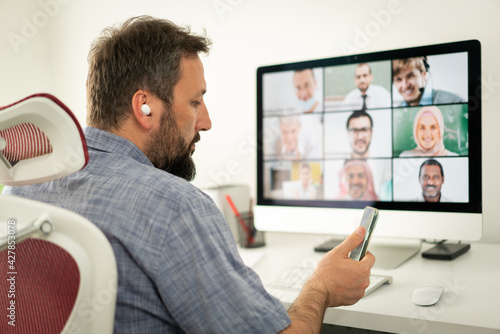 Mid adult man having online conference working at home