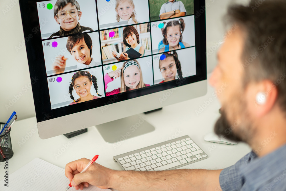 Obraz premium Male teacher having online conference with school children working at home