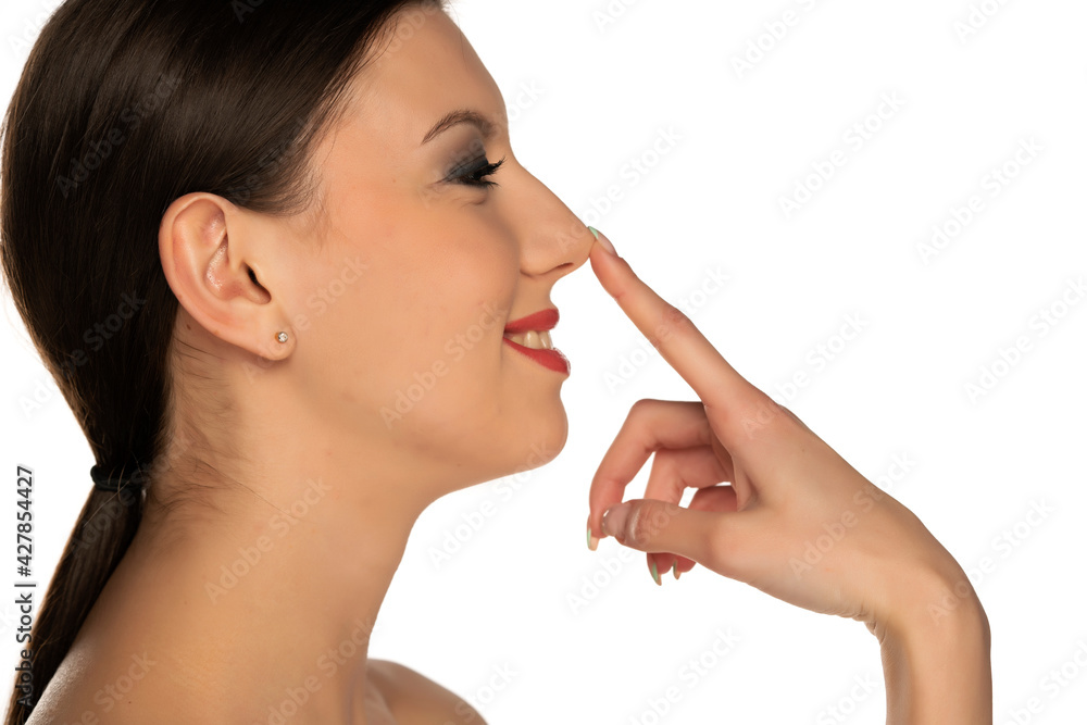 profile of a young smiling woman touching her nose profile of a young smiling woman touching her nose