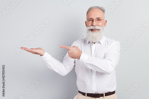 Photo of aged man happy positive smile point finger poduct advet select suggest isolated over grey color background photo