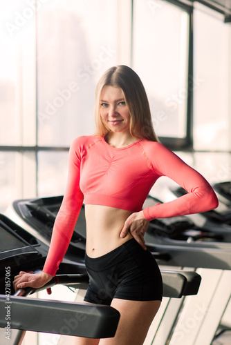 A sporty woman standing on treadmill at gym. Fitness concept, Healthy, Sport, Lifestyle © Ivan Zelenin