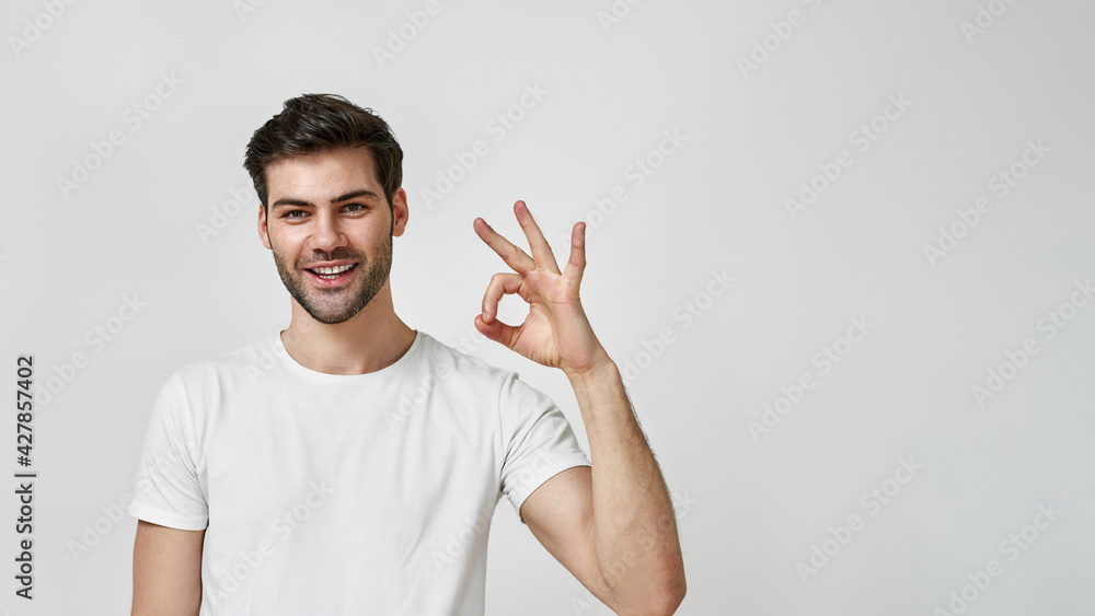Young man in white t-shirt showing okay gesture Young man in white t-shirt showing okay gesture