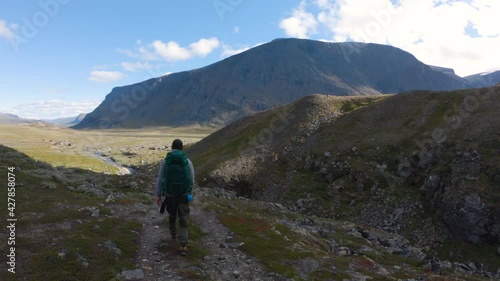 Male hiker walking in the nature of Northern Sweden. A small stream and mountains can be seen in the background. photo