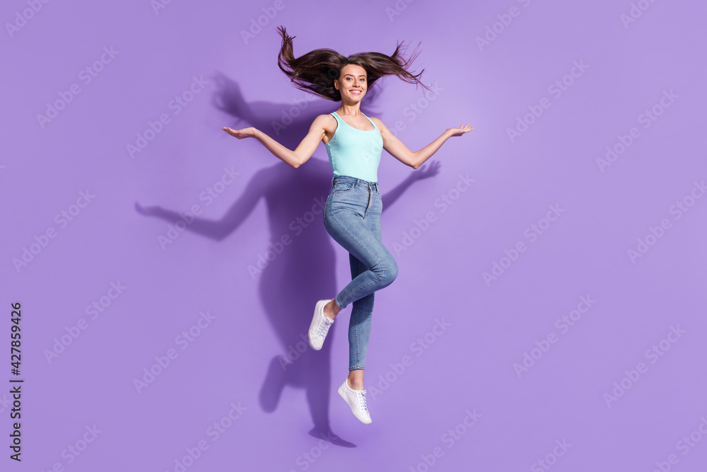 Full length portrait of charming person jumping raise hands hair flying isolated on purple color background
