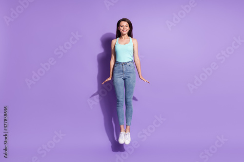 Full size portrait of cheerful charming lady jump high beaming smile isolated on purple color background