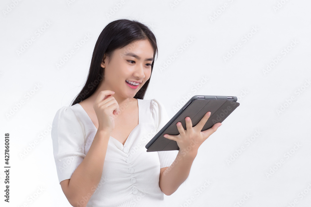 Asian beautiful woman in white shirt look at on tablet in her hand excitedly on white background. Asian beautiful woman in white shirt look at on tablet in her hand excitedly on white background.